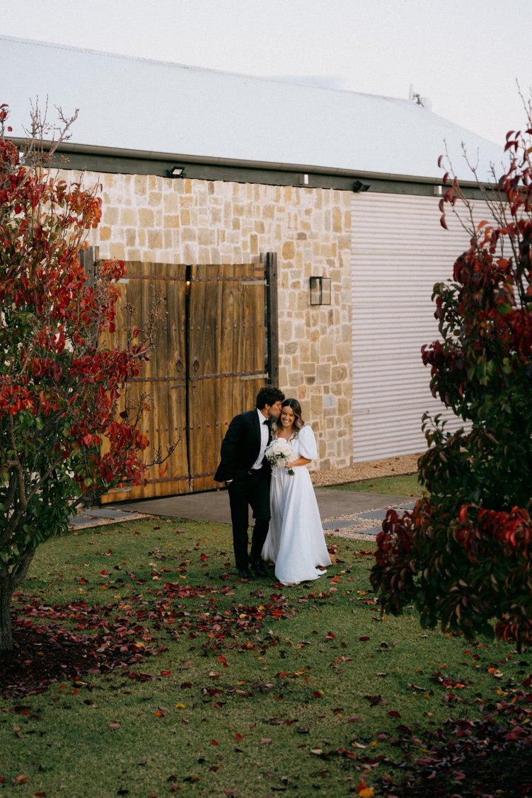 A couple at the timber barn doors in the hedged courtyard