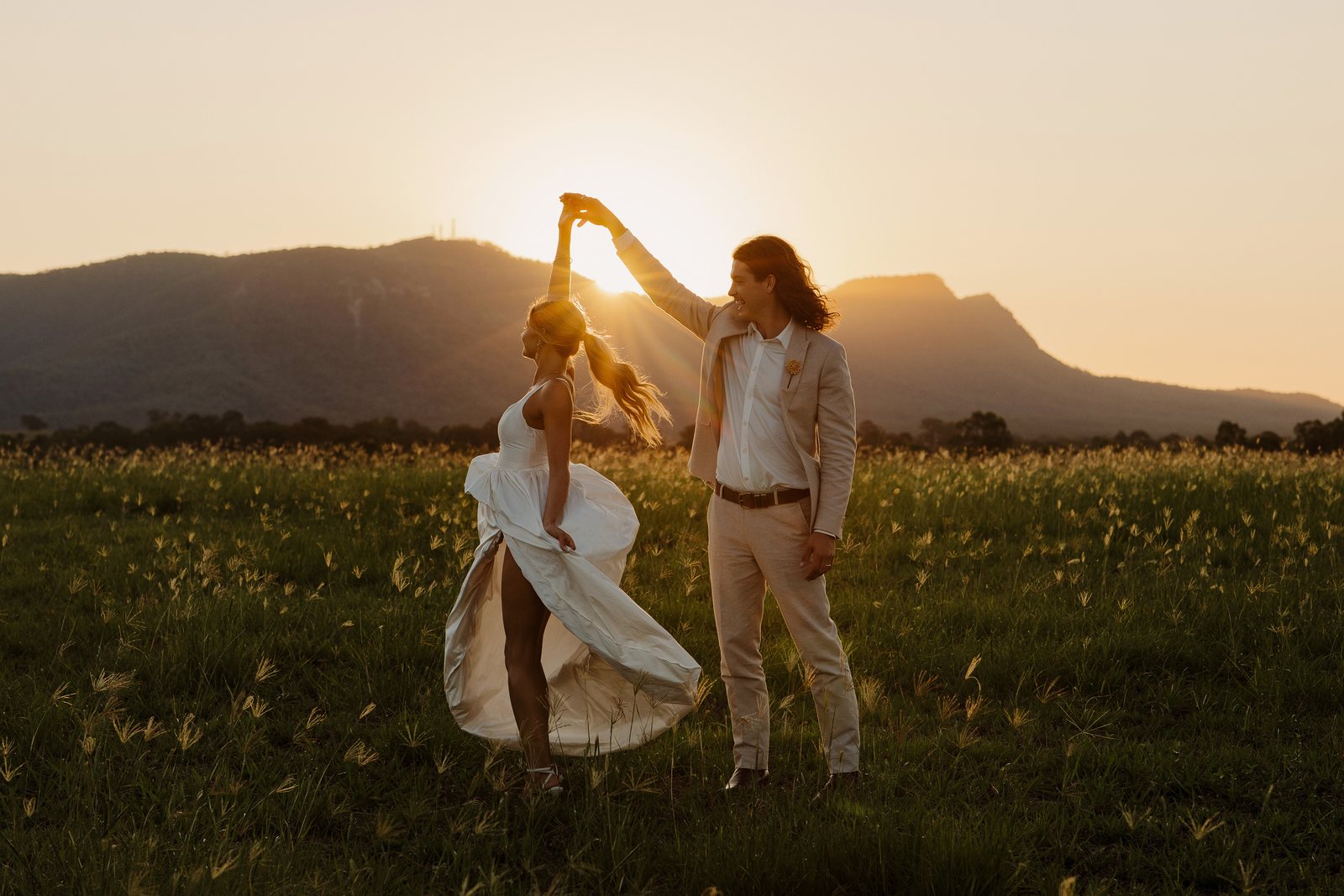 A couple dancing in the paddock at sunset with the range behind