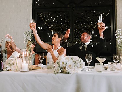 A couple toasting at the head table as sparklers go off